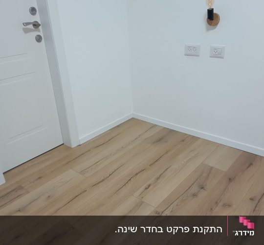 רצפת פרקט בחדר עם דלת ושקעי חשמל